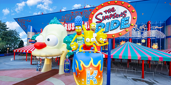 Os personagens Homer, Marge, Lisa, Bart e Maggie Simpson estão em um carrinho, em frente à atração The Simpsons no Universal Studios Florida™