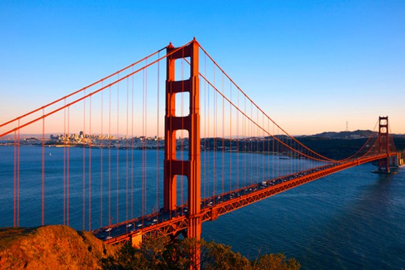 Vista lateral da Golden Gate Bridge em San Francisco ao entardecer. Também se vê o mar aberto e a Ilha Alcatraz.