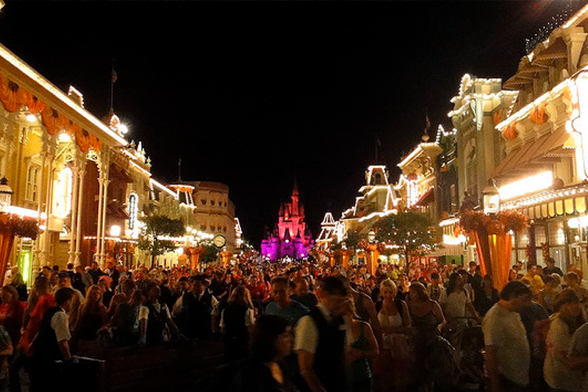 Ao fundo, o Castelo da Cinderela do Magic Kingdom. No plano da frente, muitas pessoas lotam o parque.