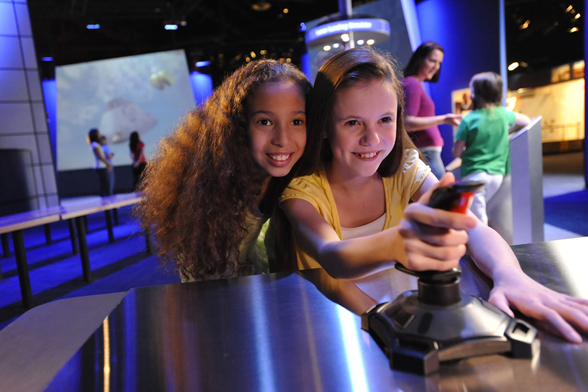 Duas meninas brincam em um simulador de exploração do espaço no Kennedy Space Center Visitor Complex