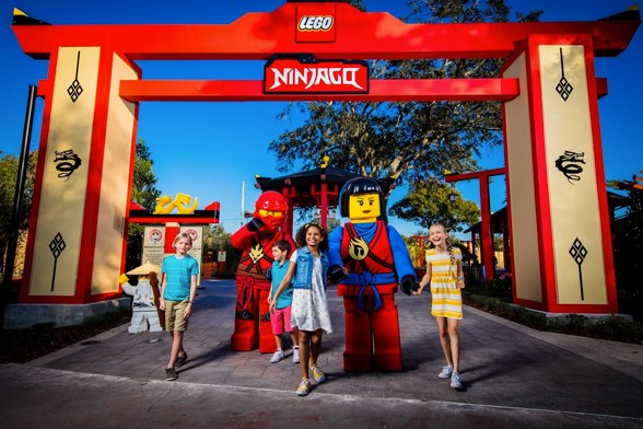 Quatro crianças interagem com dois personagens feitos de blocos LEGO® em tamanho real na entrada do Ninjago World no LEGOLAND® Florida Resort durante o evento especial NINJAGO® Days.