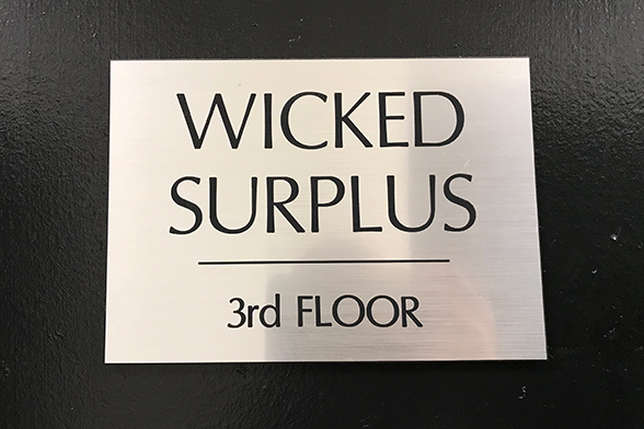 Placa do estoque de figurinos excedentes de Wicked, em Nova York, que diz "Wicked Surplus, 3rd floor".