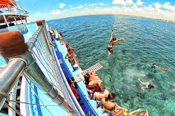 Durante o dia, uma mulher pula ao mar do trampolin do Dancer Cruise em Cancun.