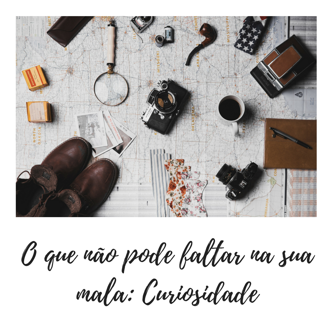 Dicas de bancos de imagens e vídeos gratuitos: Imagem de uma mesa com itens de viagem como câmeras, mapas, sapatos, documentos, com a frase "O que não pode faltar na sua mala: Curiosidade."