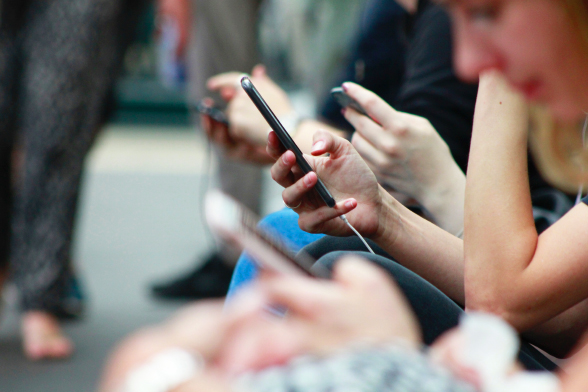 Pessoas na rua usando o celular.